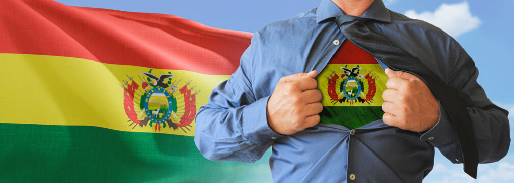 A businessman opening his shirt like super hero with Bolivia flag and shows how patriotic he is by revealing his countries flag beneath printed on a t-shirt.