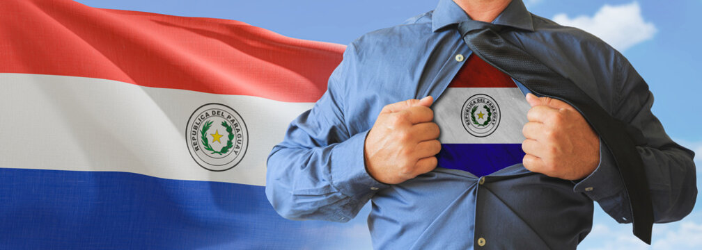A businessman opening his shirt like super hero with Paraguay flag and shows how patriotic he is by revealing his countries flag beneath printed on a t-shirt.