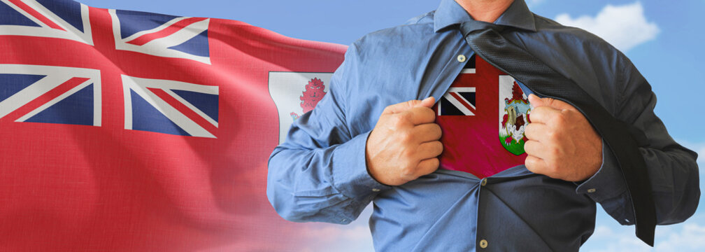 A businessman opening his shirt like super hero with Bermuda flag and shows how patriotic he is by revealing his countries flag beneath printed on a t-shirt.