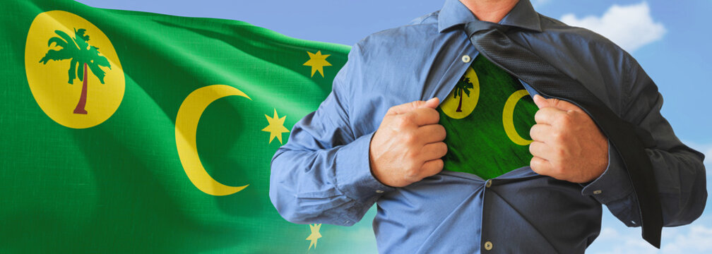 A businessman opening his shirt like super hero with Cocos Keeling Islands flag and shows how patriotic he is by revealing his countries flag beneath printed on a t-shirt.