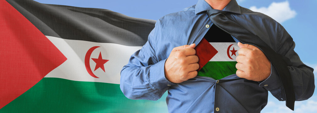 A businessman opening his shirt like super hero with Western Sahara flag and shows how patriotic he is by revealing his countries flag beneath printed on a t-shirt.