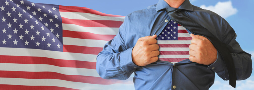 A businessman opening his shirt like super hero with American flag and shows how patriotic he is by revealing his countries flag beneath printed on a t-shirt.