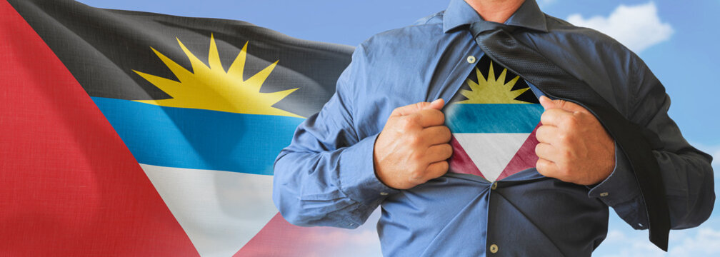 A businessman opening his shirt like super hero with Antigua and Barbuda flag and shows how patriotic he is by revealing his countries flag beneath printed on a t-shirt.