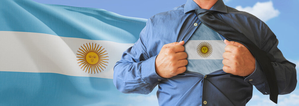 A businessman opening his shirt like super hero with Argentina flag and shows how patriotic he is by revealing his countries flag beneath printed on a t-shirt.