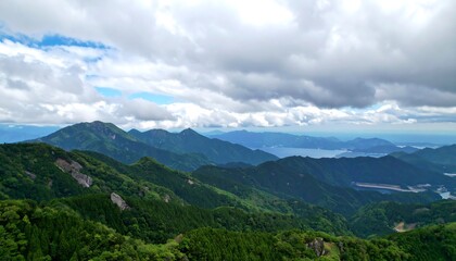 A panoramic vista of lush green mountains cascading down to a tranquil bay, framed by a dramatic sky filled with fluffy clouds.