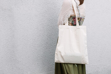 Young white woman holding black eco bag on arm shoulder or hand, street wall at background. city...