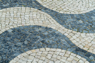Calcada in Portugal features intricate cobblestone designs with alternating patterns. Stones create wave effect, highlighting artistry of local craftsmanship.