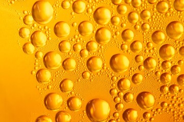 Detailed macro photograph of golden bubbles in a carbonated drink, abstract background with sparkling fizzy texture