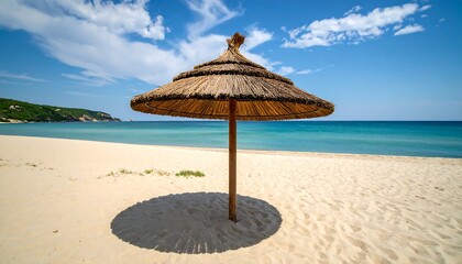 Tranquil beach scene under a thatched umbrella, showcasing soft sand and a serene ocean vista.