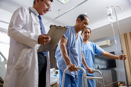 Doctor and nurse supporting patient to use walker in walking exercise after operation surgery for rehabilitation and physical therapy and recovery stage