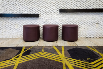 Leather ottoman stools against a wall in a modern office lounge