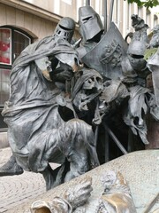 Bronze statue depicting medieval knights tumbling from horses during intense battlefield combat