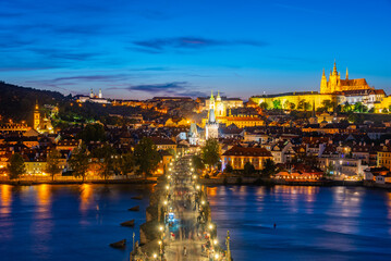 Sunset view of people passing Charles bridge towards Prague cast