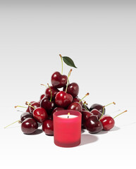Fresh cherries with red candle composition for home decor on white background