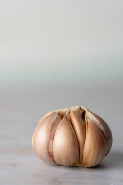 Bulb of purple garlic with the skin removed on a light surface 