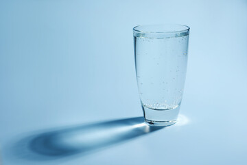 Refreshing soda water in glass on light blue background, closeup. Space for text