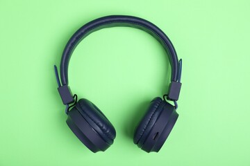 Pair of stylish blue headphones on light green background, top view