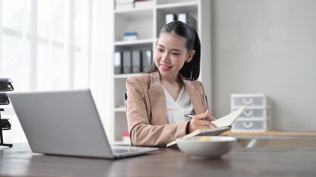 Businesswoman working from home office taking notes watching webinar