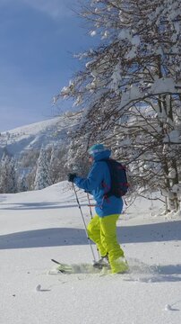 SLOW MOTION: Young man hikes in the pristine white countryside to splitboard off piste in scenic Julian Alps. Active male tourist on ski touring vacation in rural Slovenia hikes in deep powder snow.
