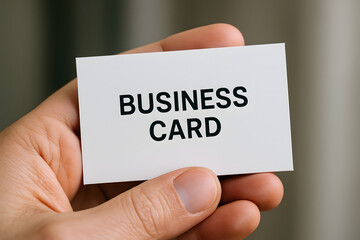 A person's hand holding a white business card with the words 'BUSINESS CARD' printed in black.