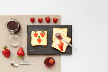 Board of tasty toasts with sweet strawberry jam on grey background