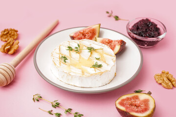 Plate of tasty baked Camembert cheese on pink background