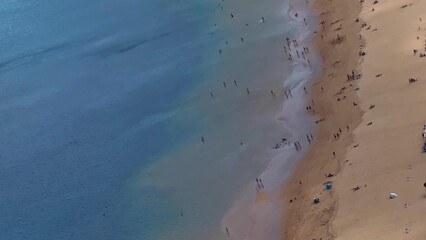 Aerial view of a vibrant beach scene with tourists enjoying sunshine and making memories