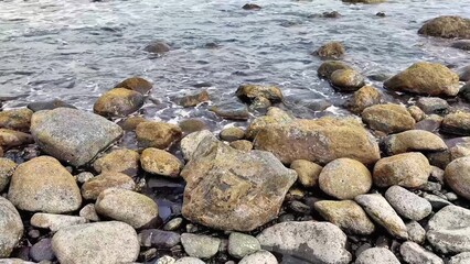 A peaceful coastal scene with a rocky shoreline and gentle waves lapping against it