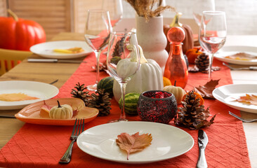 Autumn table setting with pumpkins, dry leaves and pine cones