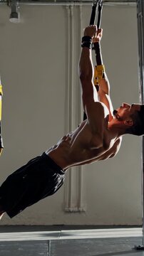 Vertical video athlete performing a bodyweight row exercise using suspension straps, highlighting the different stages of movement and the engagement of muscles