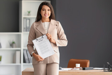 Young businesswoman holding clipboard with documents near workplace in office