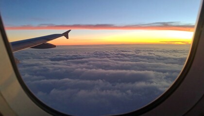 Airplane window view of sunset over clouds (1)