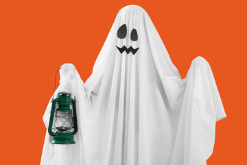 Person in Halloween costume of ghost with lantern on orange background