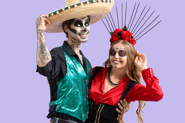 Young happy couple dressed for Mexico's Day of the Dead (El Dia de Muertos) on purple background