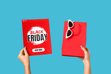 Hands with shopping bag and card on blue background. Black Friday sale