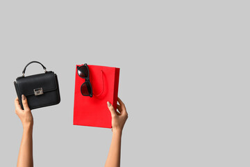 Hands with shopping bag and accessories on grey background. Black Friday sale