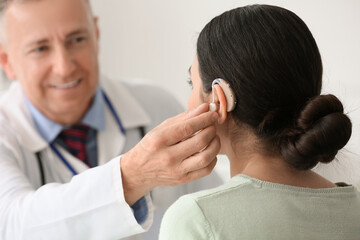 Fototapeta premium Young woman with hearing aid visiting doctor in clinic, closeup
