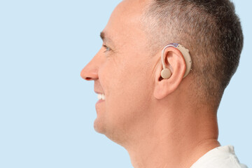 Obraz premium Mature man with hearing aid on blue background, closeup