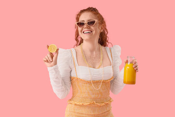 Young redhead woman in sunglasses with turmeric drink on pink background