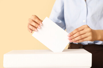 Voting woman near ballot box on beige background, closeup