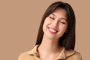 Fototapeta premium Smiling young woman on beige background, closeup