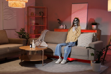 Human skeleton model dressed as woman sitting on sofa in living room at night