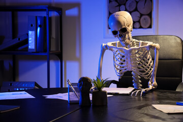Human skeleton model sitting in office at night