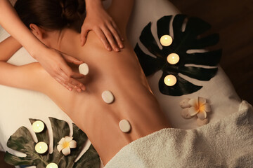 Woman getting back massage with stones in dark spa salon, top view