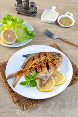 Fried sea bass with garlic on a white plate