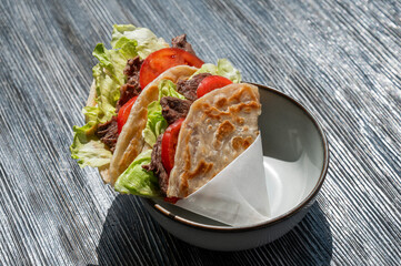 Homemade flatbread with beef and tomatoes on a table in a cafe. 