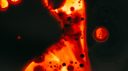 Paint droplet. Spill ink texture. Defocused dark orange red glowing neon water liquid oil bubble flowing fluid on black abstract art light background.