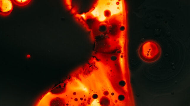 Paint droplet. Spill ink texture. Defocused dark orange red glowing neon water liquid oil bubble flowing fluid on black abstract art light background.