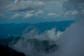 Obraz premium Amazing landscape fog mountain clouds scenery. Beautiful Mountain landscape foggy windy mountain range green landscape asian farm. Landscape mountain green field meadow white cloud blue sky sunrise