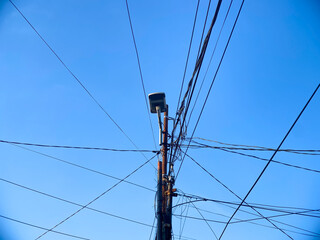 Tangled Wires and Street Light on Utility Pole Against Blue Sky